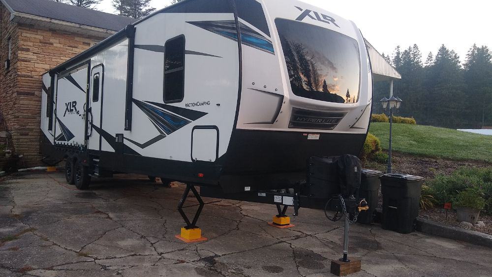 5th wheel RV being stored on a driveway with the jacks down on stabilizer blocks
