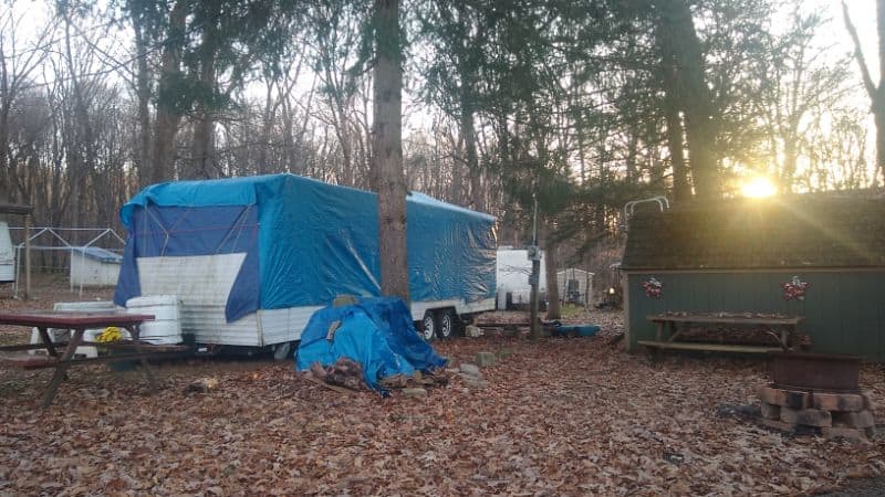 A trashy RV covered with a blue poly tarpaulin