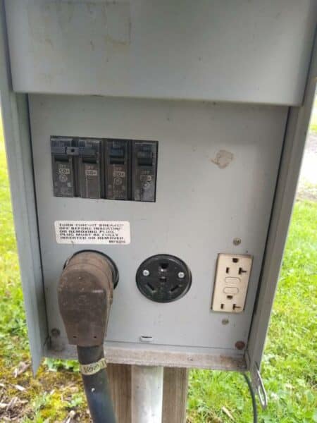 A 100-amp RV power pedestal with shore power cord attached to the 50-amp receptacle. 