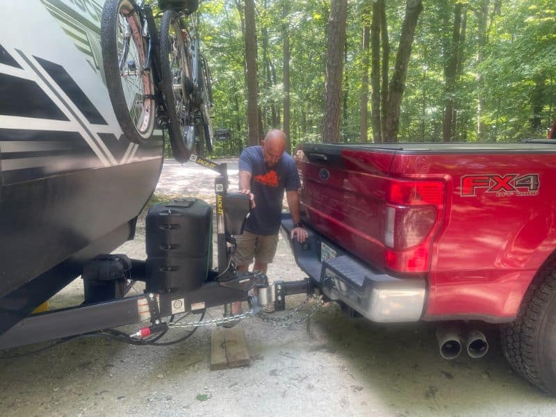 Man setting up weight-distribution anti-sway hitch on travel trailer camper
