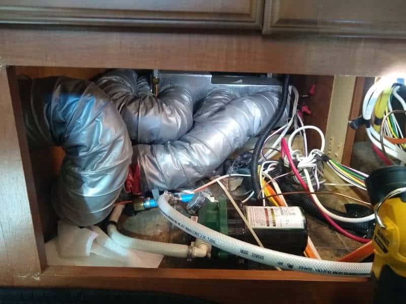 Messy RV flexible ductwork beneath a cabinet.